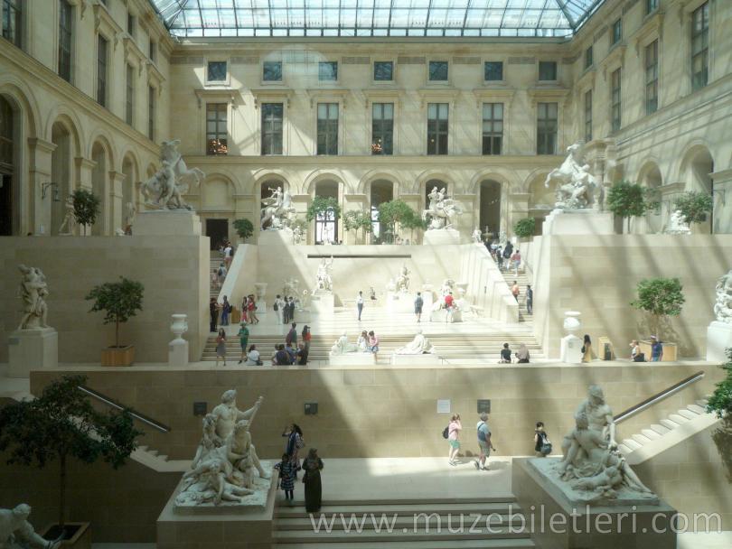 Louvre Müzesi ziyaretçileri heykelleri geziyor.