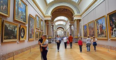 Louvre Müzesi'nin ziyaretçileri resim galerilerini geziyor.