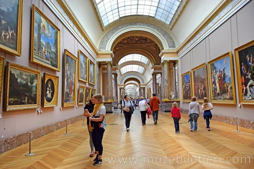 Louvre Müzesi'nin ziyaretçileri resim galerilerini geziyor.